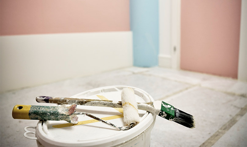 Binsel und Farbrolle auf dem Deckel eines Farbkübels