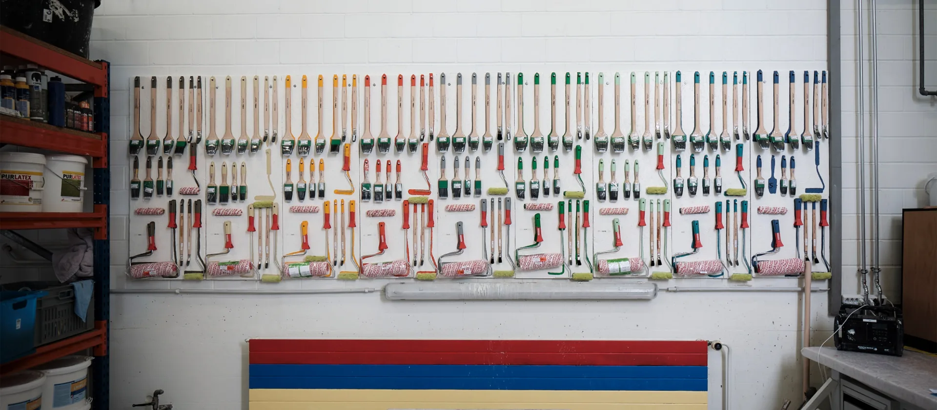 Eine Wand mit mehreren Sets von Pinseln und anderen Werkzeugen, die ordentlich aufgehängt sind.